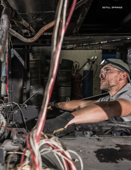 Mechanic inside RV Coach Bus Diesel Engine Compartment